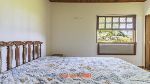 a bedroom with a large bed with a window at Casa de campo em Atibaia com Lareira e Piscina in Atibaia