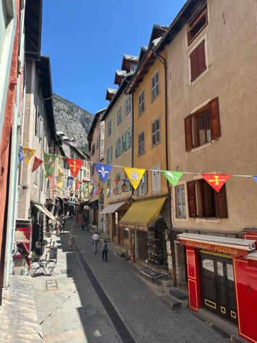 an alley with flags and people walking down a street at Aroma Cite Vauban in Briançon