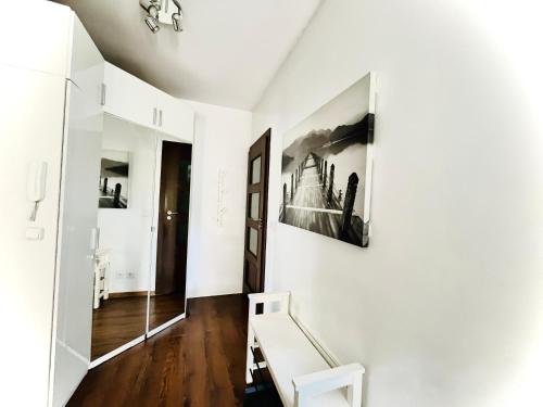 un corridoio bianco con una panchina e una foto sul muro di Bronowice Residence Blue - Homey Apartment with Garden and Parking a Cracovia