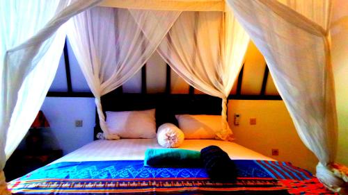 a bedroom with a bed with a canopy at Ina Gili Guesthouse in Gili Air