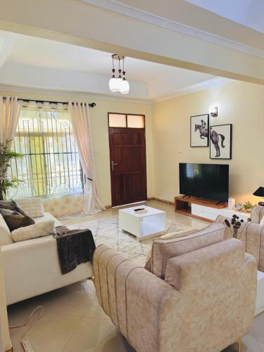 a living room with two couches and a tv at In arusha nests in Arusha