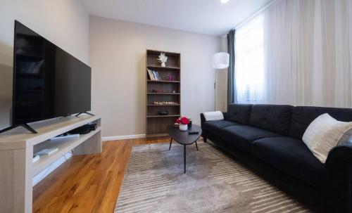 a living room with a black couch and a television at Sunny 4BR/2BA Retreat in Morningside Heights, NYC in New York