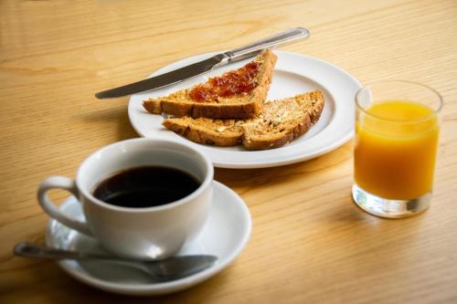 a plate of toast and a cup of coffee and a glass of orange juice at Summerlands Guest House in Torquay