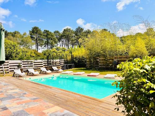 une piscine avec des chaises et une terrasse en bois dans l'établissement Seawest avec piscine à 5 min de l'océan, à Vielle-Saint-Girons