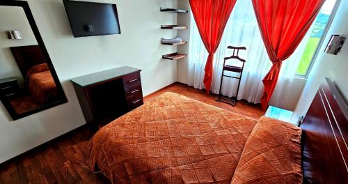 a bedroom with a bed and a television and red curtains at Hotel Avanty in Ipiales