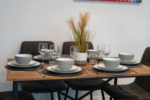 a wooden table with plates and wine glasses on it at 3-bed Chelmsford apt w garden in Chelmsford