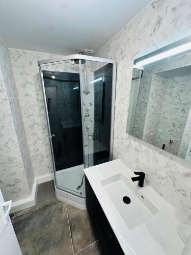 une salle de bain blanche avec une douche et un lavabo dans l'établissement Appartement tout neuf avec patio - 31, à Dax