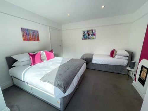 a bedroom with two beds with pink pillows at 3-bed Chelmsford apt w garden in Chelmsford