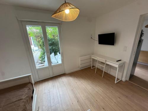een witte kamer met een bureau en een raam bij Appartement tout neuf avec patio - 31 in Dax
