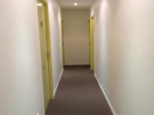 an empty hallway with two yellow doors and a hallwayngth at Hôtel La Fontaine in Lourdes