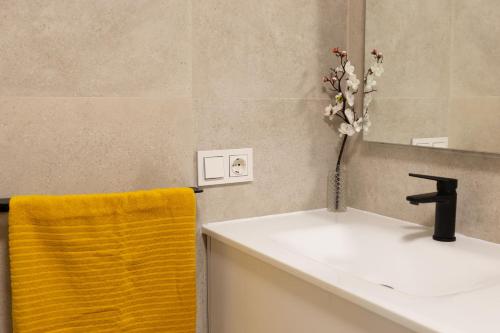 a bathroom with a sink and a vase of flowers at Ático con terraza, garaje y muy céntrico in O Grove