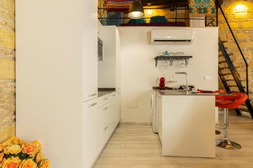 a small kitchen with white cabinets and a red stool at Exclusive Boutique in Jerez de la Frontera