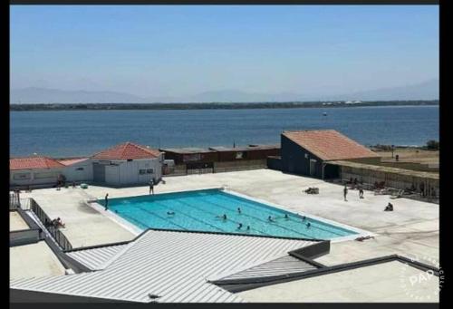 une grande piscine à côté d'un grand plan d'eau dans l'établissement Appartement familial et pratique, au Barcarès