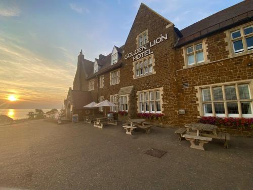 a brick building with picnic tables in front of it at The Golden Lion Hotel in Hunstanton
