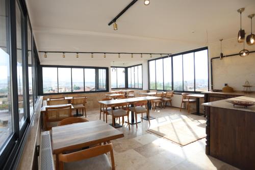 a restaurant with tables and chairs and large windows at Erdu Cappadocia Stone House in Avanos
