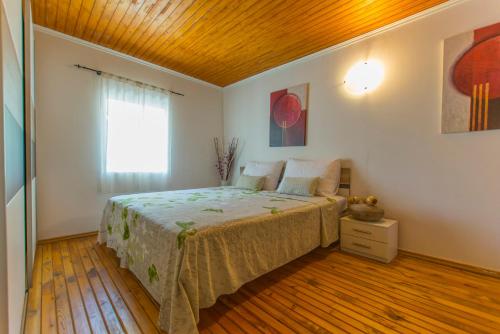 a bedroom with a bed with a wooden ceiling at House My dream house in Karlobag