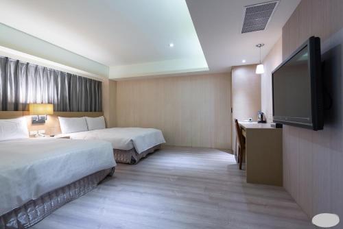 a hotel room with two beds and a flat screen tv at 巴黎商旅 Paris Hotel in Kaohsiung