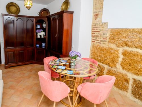 comedor con mesa de cristal y sillas rosas en Puerta Romana, en Carmona