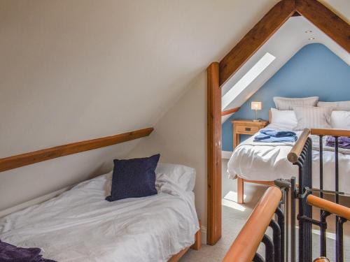 a attic bedroom with two bunk beds and a ladder at The Old Paybarn - Uk39378 in Snettisham