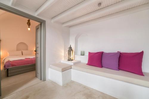 a bedroom with white walls and pink pillows at Kampanario Luxury Villa in Megalochori