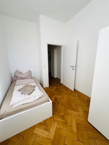 a white bedroom with a bed and a wooden floor at Leoben 3 rooms 3 people Top 4 in Leitendorf