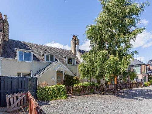 ein Haus mit einem Zaun und einem Baum in der Unterkunft Willow Cottage - Uk39244 in Inverness