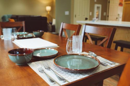 a wooden table with plates and silverware on it at Lakeshore Lodging Apartment G in Homer