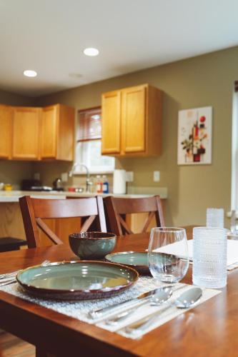 a wooden table with plates and wine glasses on it at Lakeshore Lodging Apartment G in Homer