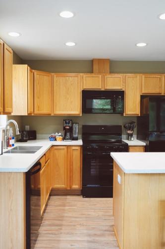 a kitchen with wooden cabinets and black appliances at Lakeshore Lodging Apartment F in Homer