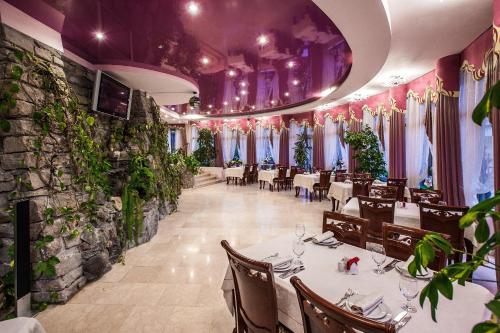 una sala da pranzo con tavoli, sedie e piante di Rest-Matsesta Hotel a Sochi