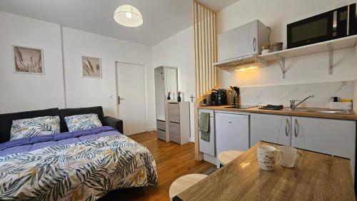 une chambre avec un lit et une cuisine avec une table dans l'établissement Les studios du Cercle, à Limoges