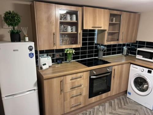 a kitchen with wooden cabinets and a white refrigerator at Abbeygreen Village House in Lesmahagow