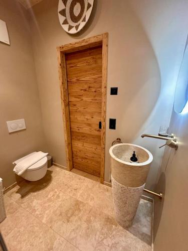 a bathroom with a toilet and a wooden door at Luxury family Chalet with extraordinary Mountain views in Trin