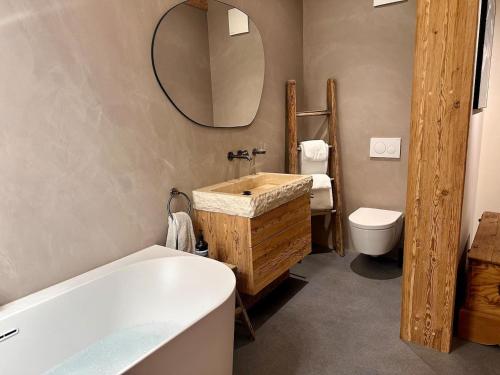 a bathroom with a tub and a sink and a mirror at Luxury family Chalet with extraordinary Mountain views in Trin