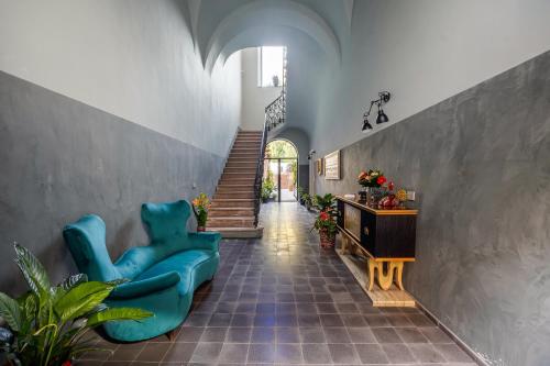 a hallway with a blue chair and a table and stairs at Creuza De Ma in Riposto