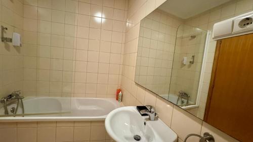 a bathroom with a sink and a bath tub at Raízes da Vinha - Quartos & Chalé na Serra da Estrela in Carragozela