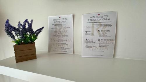a table with two signs and a vase with purple flowers at Raízes da Vinha - Quartos & Chalé na Serra da Estrela in Carragozela