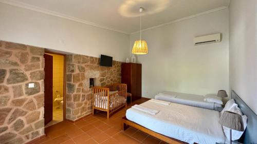 a bedroom with a bed and a stone wall at Raízes da Vinha - Quartos & Chalé na Serra da Estrela in Carragozela