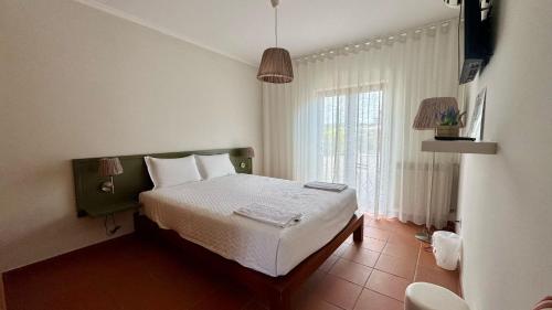 a bedroom with a bed and a large window at Raízes da Vinha - Quartos & Chalé na Serra da Estrela in Carragozela