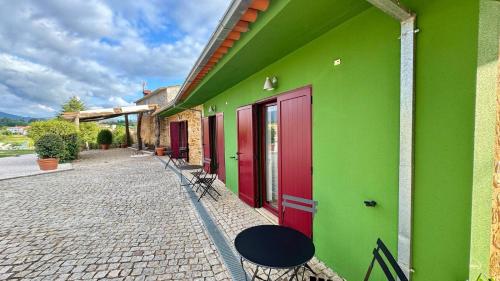 a building with green and red doors and a sidewalk at Raízes da Vinha - Quartos & Chalé na Serra da Estrela in Carragozela