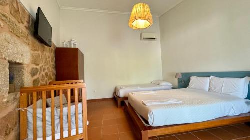 a bedroom with two beds and a crib in it at Raízes da Vinha - Quartos & Chalé na Serra da Estrela in Carragozela