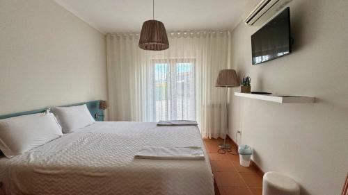 a bedroom with a bed and a television on the wall at Raízes da Vinha - Quartos & Chalé na Serra da Estrela in Carragozela