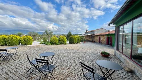 a patio with tables and chairs on a brick courtyard at Raízes da Vinha - Quartos & Chalé na Serra da Estrela in Carragozela