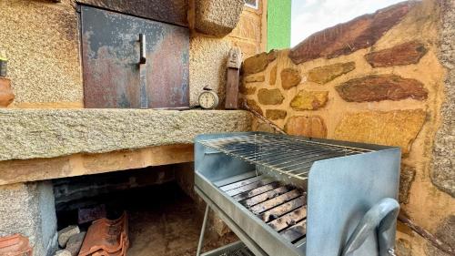 a barbecue grill sitting next to a stone wall at Raízes da Vinha - Quartos & Chalé na Serra da Estrela in Carragozela