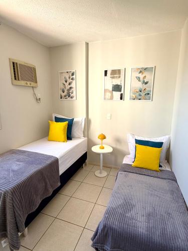 two beds with yellow and blue pillows in a room at Melhor Experiência em Cuiabá in Cuiabá