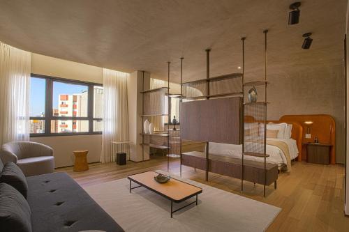 a living room with a bed and a room with a couch at QOYA Hotel Curitiba, Curio Collection by Hilton in Curitiba