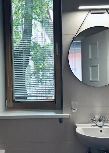 a bathroom with a mirror and a sink and a window at CENTRIKA city center apartment Self Check-in in Klaipėda