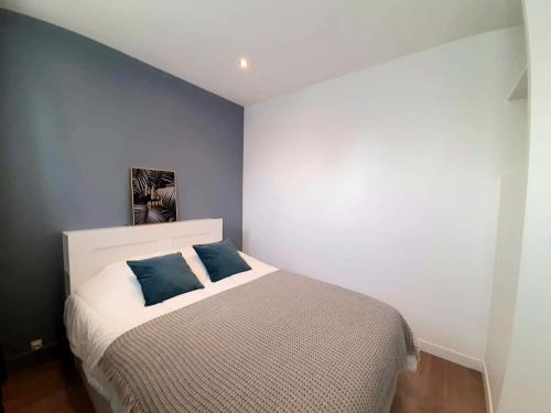 a bedroom with a bed with two blue pillows on it at Downtown Apartment with Parking Amboise 2 in Vannes