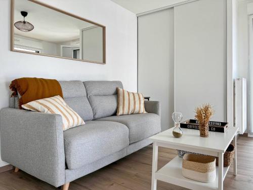 - un salon avec un canapé gris et un miroir dans l'établissement L'Emeraude - Rooftop - Salle de Fitness - Rennes, à Rennes