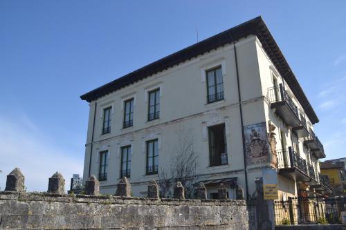a white building with a fence in front of it at Posada Casa de Valle in Colindres